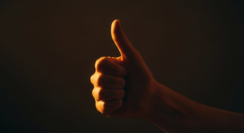 Editorial photograph close-up from the side of a hand performing the Finkelstein test, thumb tucked into a loose fist with the wrist bent toward the little finger, warm amber light, no identifiable facial features.